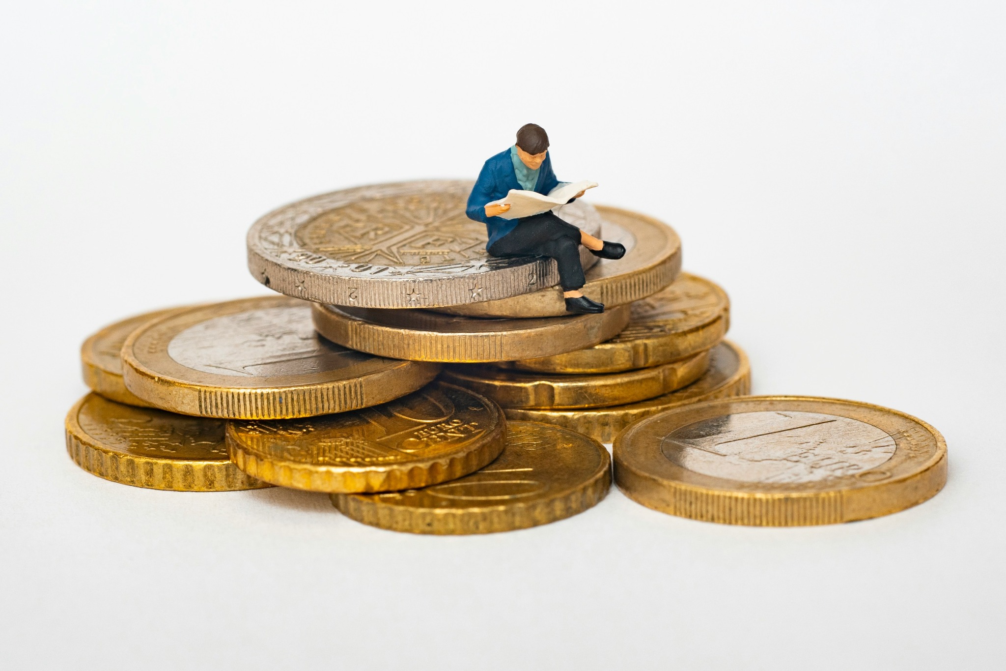 Persona leyendo sobre finanzas sentada sobre monedas: guía de bonos y renta fija de Desvío Estándar
